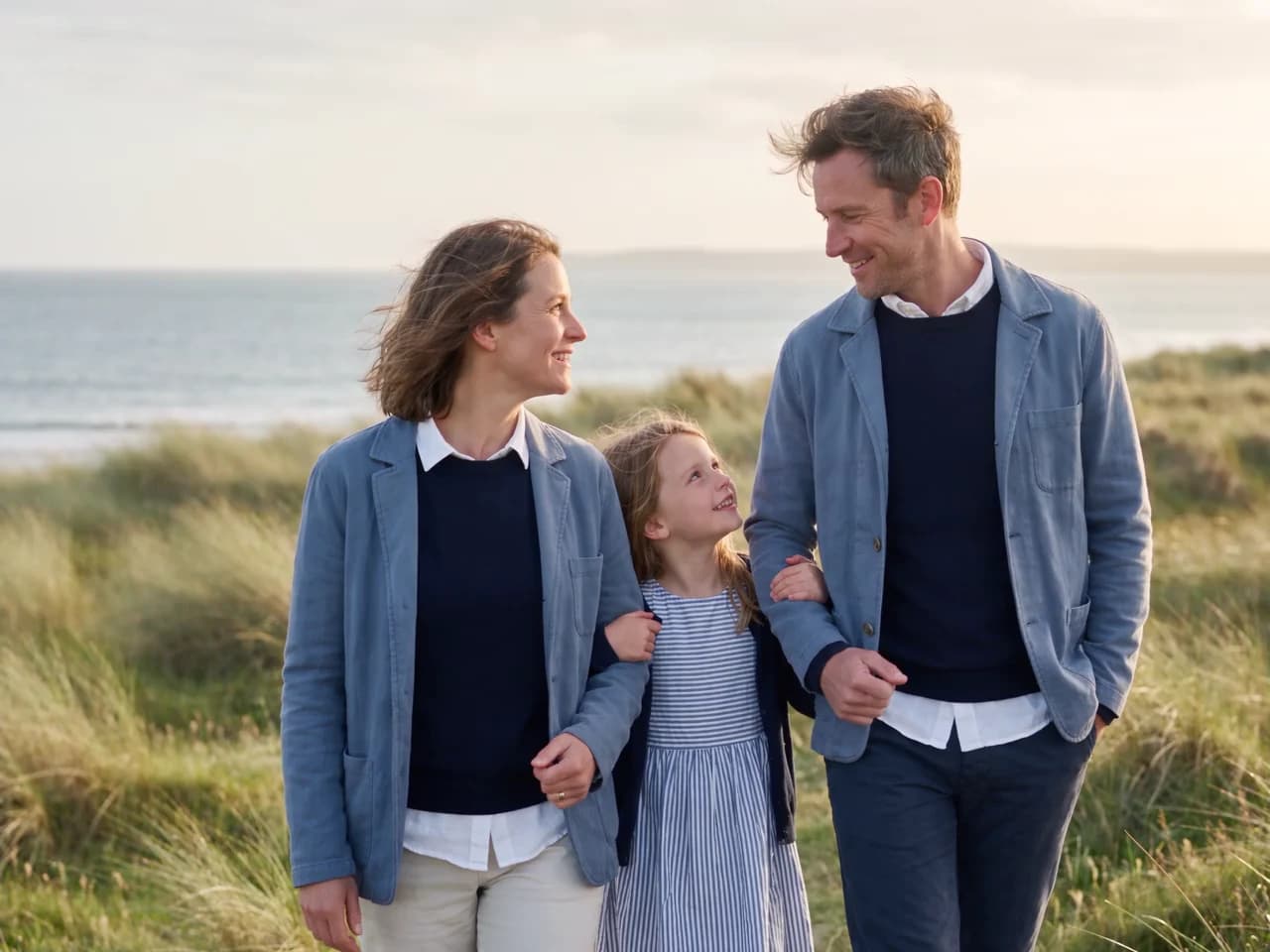 A family sharing a quiet moment in sunlit coastal grass